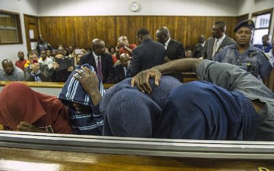 Men suspected of killing Mozambican vendor Emmanuel Sithole in Alexandra township in an apparent xenophobic attack try to hide themselves as they are arraigned at the Wynberg Magistrate's Court in Johannesburg on Tuesday. Picture: AFP PHOTO/MUJAHID SAFODIEN