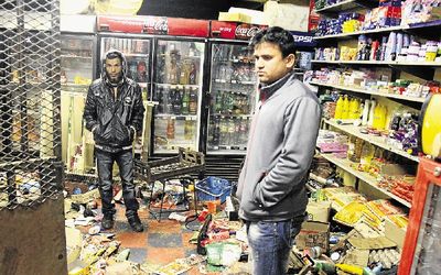 Pakistani nationals stand in their Dobsonville shop looted by residents who were angered by constant blackouts. The government can quell xenophobic violence by restructuring incentives for migrants, the writer says. File picture: SOWETAN